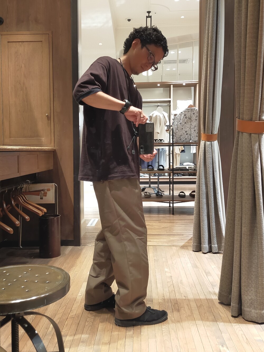 ブラウン系のTシャツ/カットソー、ベージュ系のスラックス、ブラック系のブーツを着用したメンズの夏コーディネートの2枚目の写真