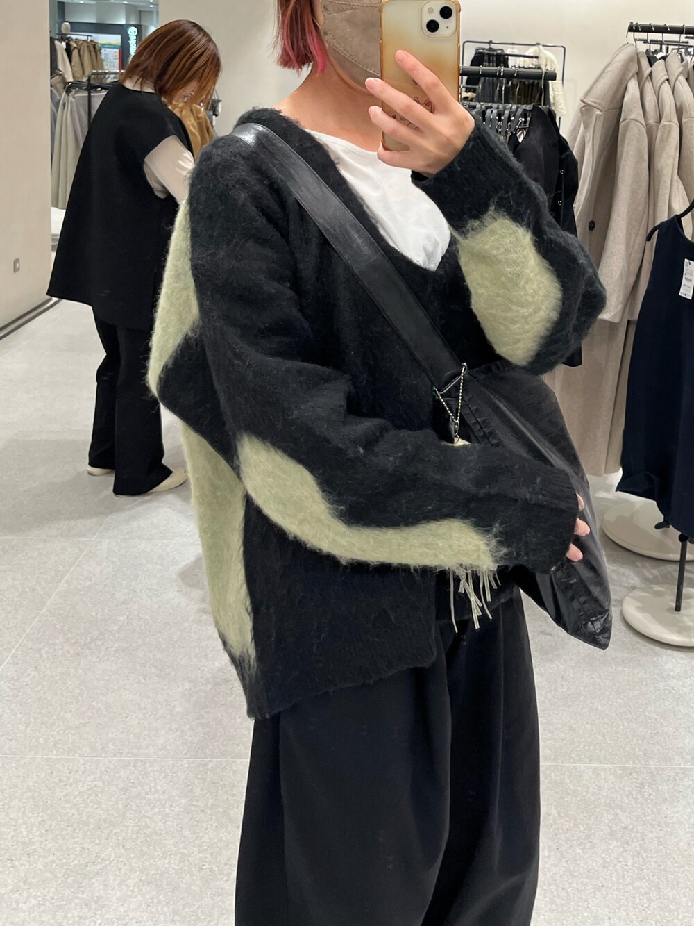 ブラック系のチノパンツ、ブラック系のショルダーバッグ、ブラック系のニット/セーターを着用したレディースの秋コーディネートの2枚目の写真