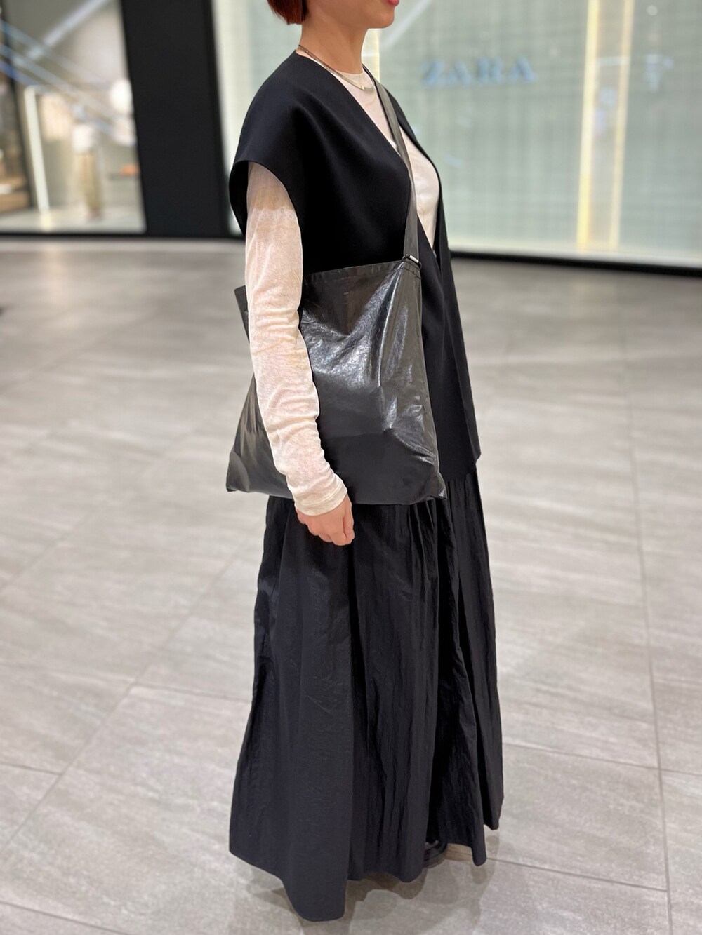 ブラック系のスカート、ブラック系のショルダーバッグ、ベージュ系のTシャツ/カットソーを着用したレディースの春コーディネートの3枚目の写真