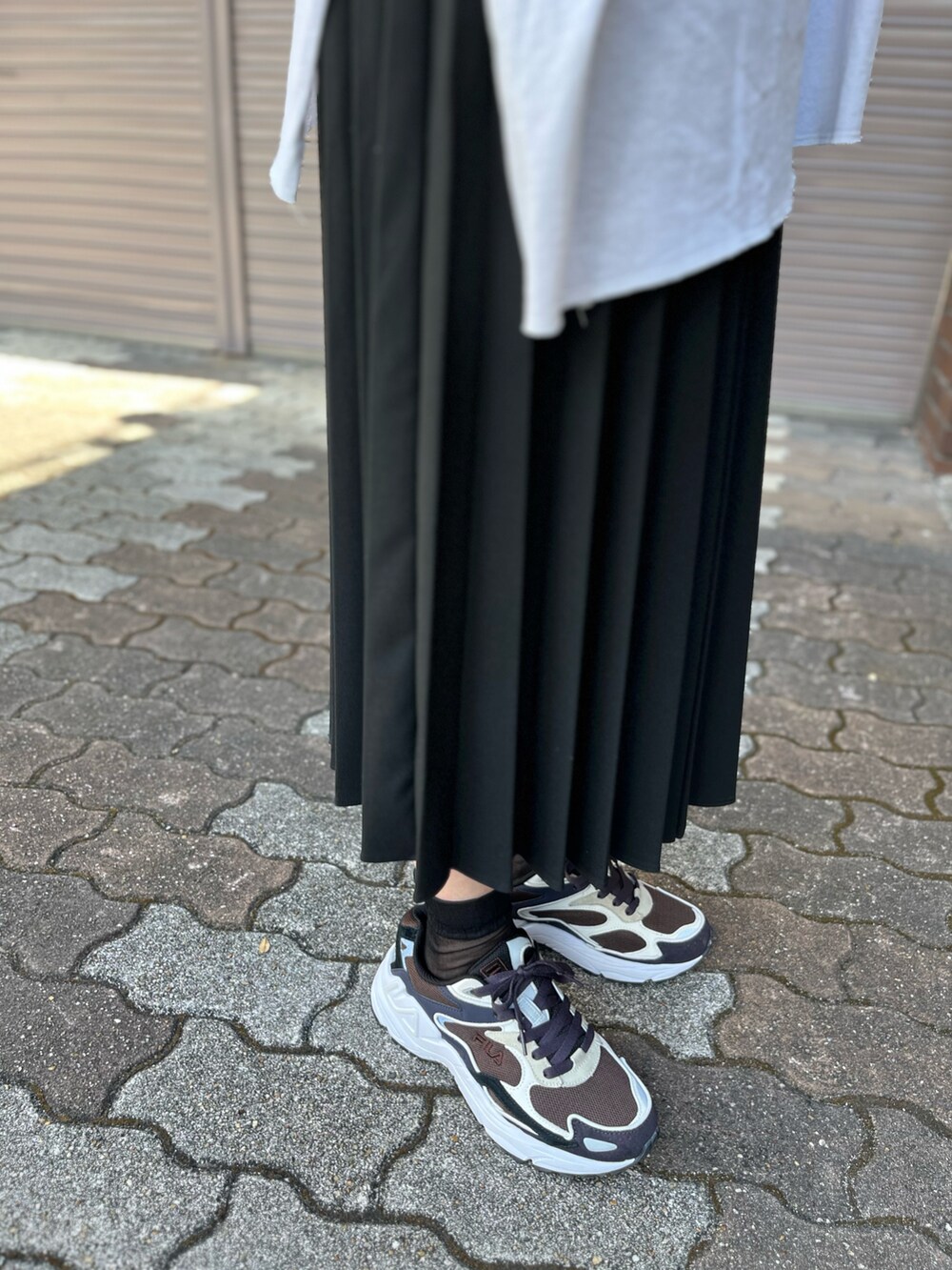 ブルー系のスニーカー、ブラック系のショルダーバッグを着用したレディースの夏コーディネートの2枚目の写真