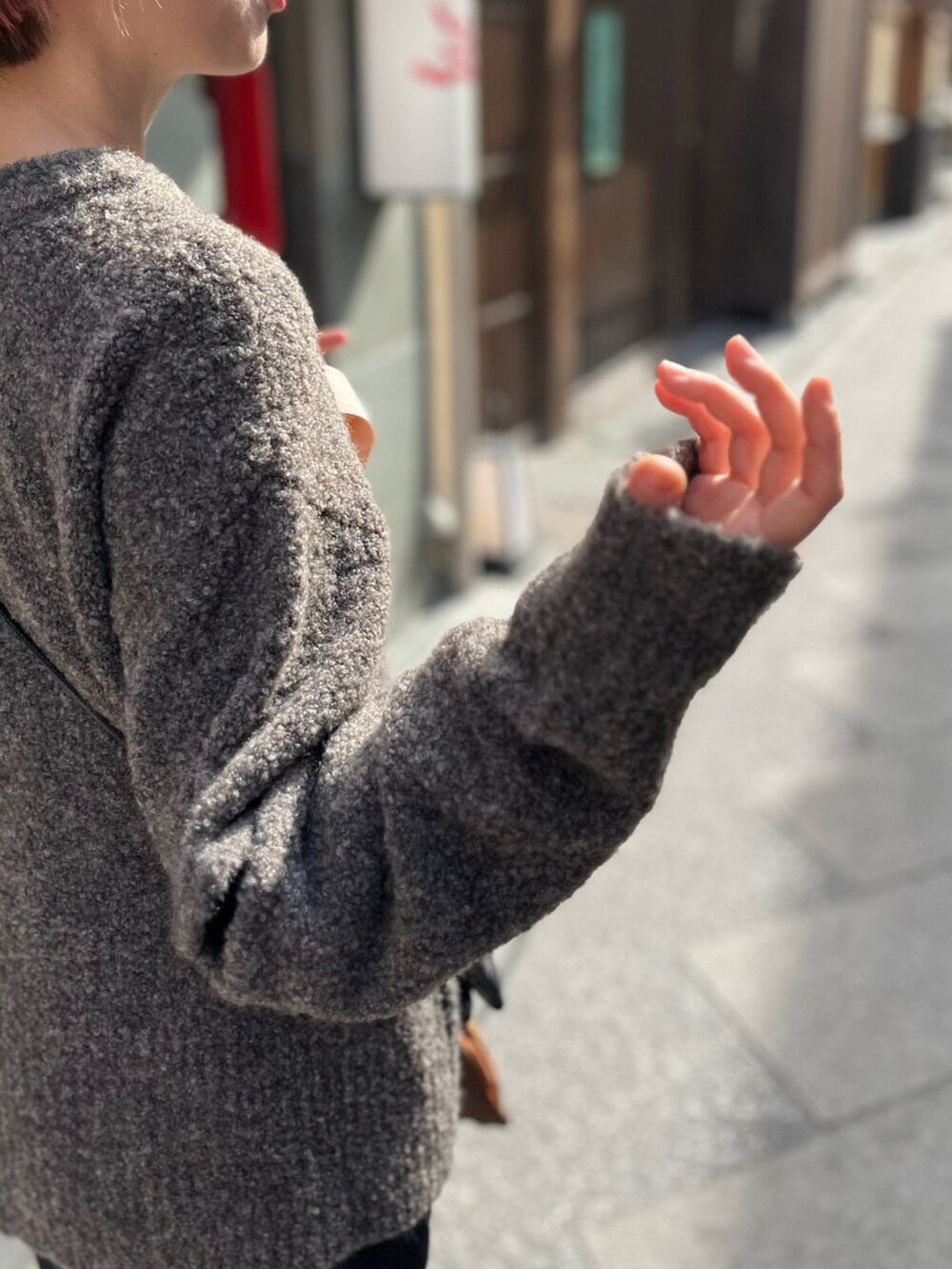 グレー系のニット/セーター、ブラック系のスカート、ブラック系のショルダーバッグを着用したレディースの冬コーディネートの2枚目の写真