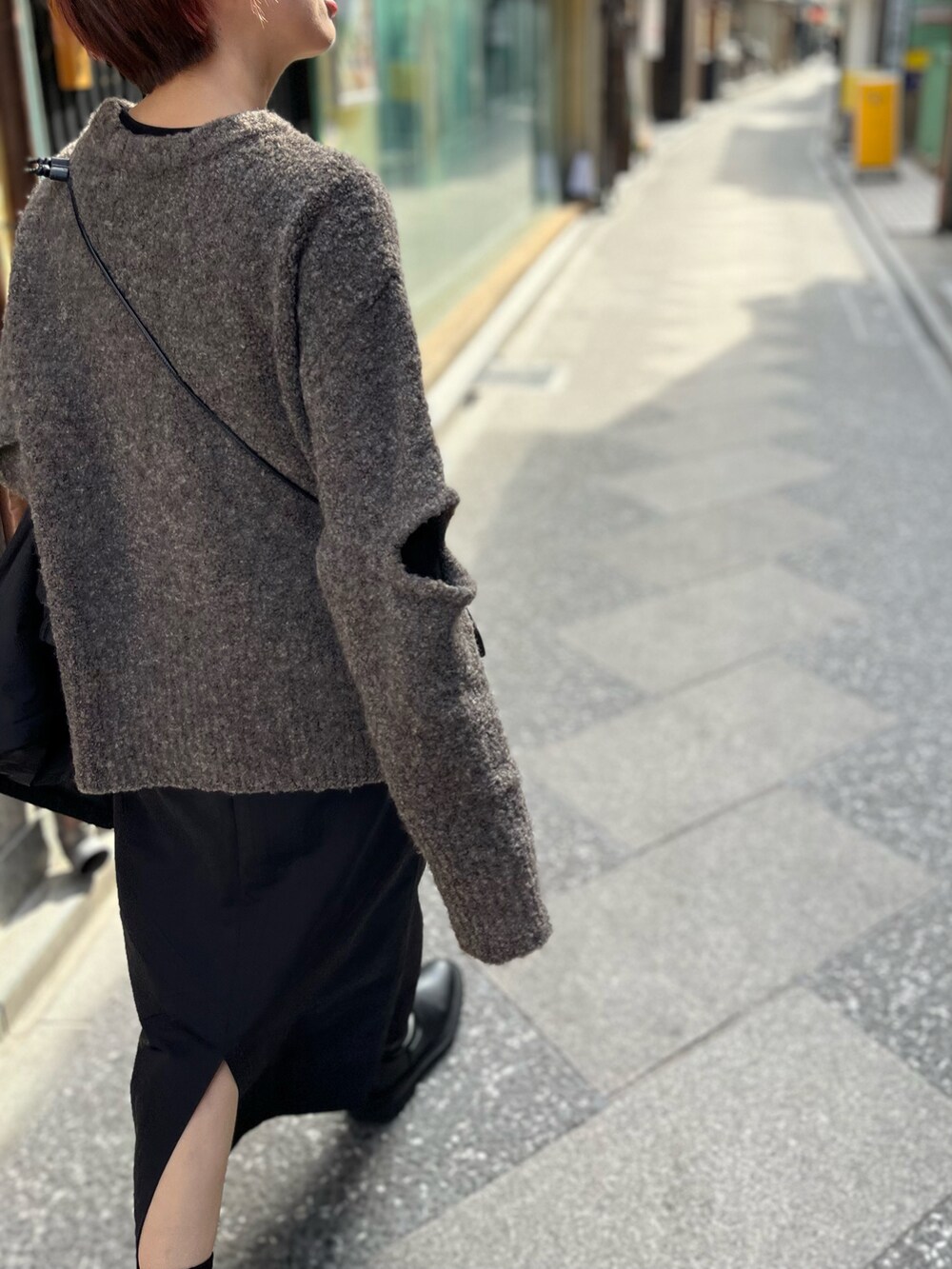 グレー系のニット/セーター、ブラック系のスカート、ブラック系のショルダーバッグを着用したレディースの冬コーディネートの3枚目の写真