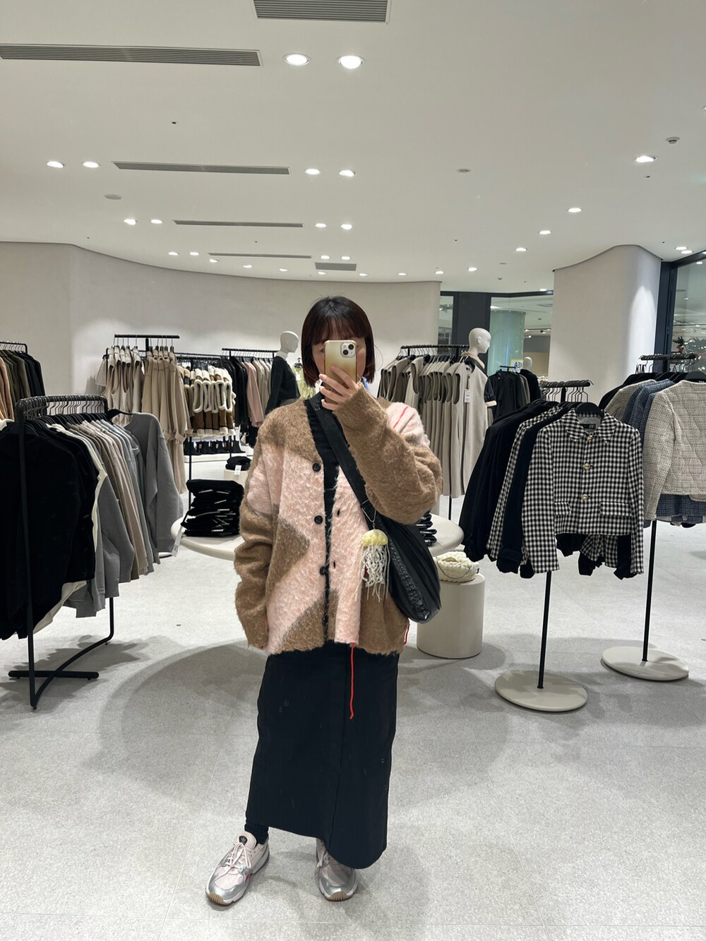 ベージュ系のカーディガン/ボレロ、ブラック系のショルダーバッグ、ブラック系のジャンパースカートを着用したレディースの冬コーディネートの4枚目の写真