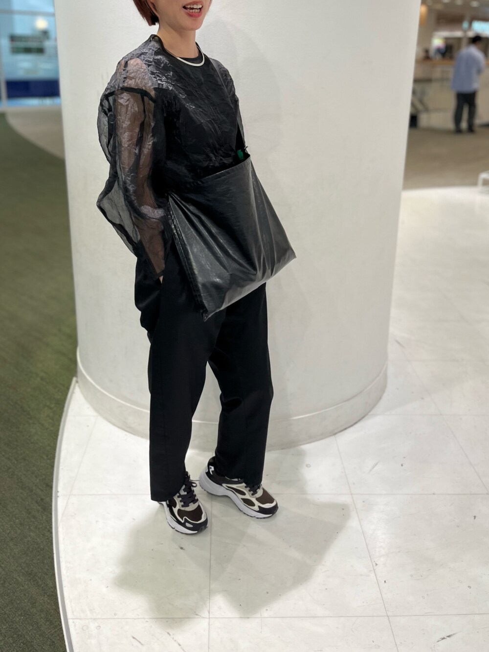 ブラック系のショルダーバッグ、ブラック系のシャツ/ブラウス、ブルー系のスニーカーを着用したレディースの春コーディネートの2枚目の写真