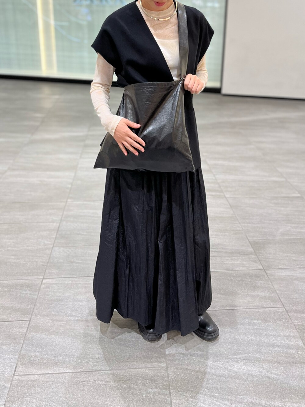 ブラック系のスカート、ブラック系のショルダーバッグ、ベージュ系のTシャツ/カットソーを着用したレディースの春コーディネートの2枚目の写真