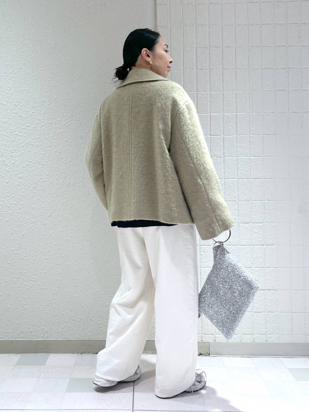 ブルー系のニット/セーター、ホワイト系のその他パンツ、シルバー系のクラッチバッグを着用したレディースの冬コーディネートの2枚目の写真