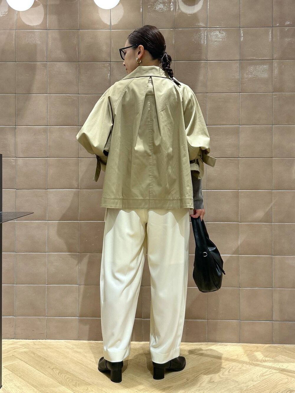 ブラック系のハンドバッグ、ホワイト系のスラックス、グレー系のTシャツ/カットソーを着用したレディースの秋コーディネートの3枚目の写真