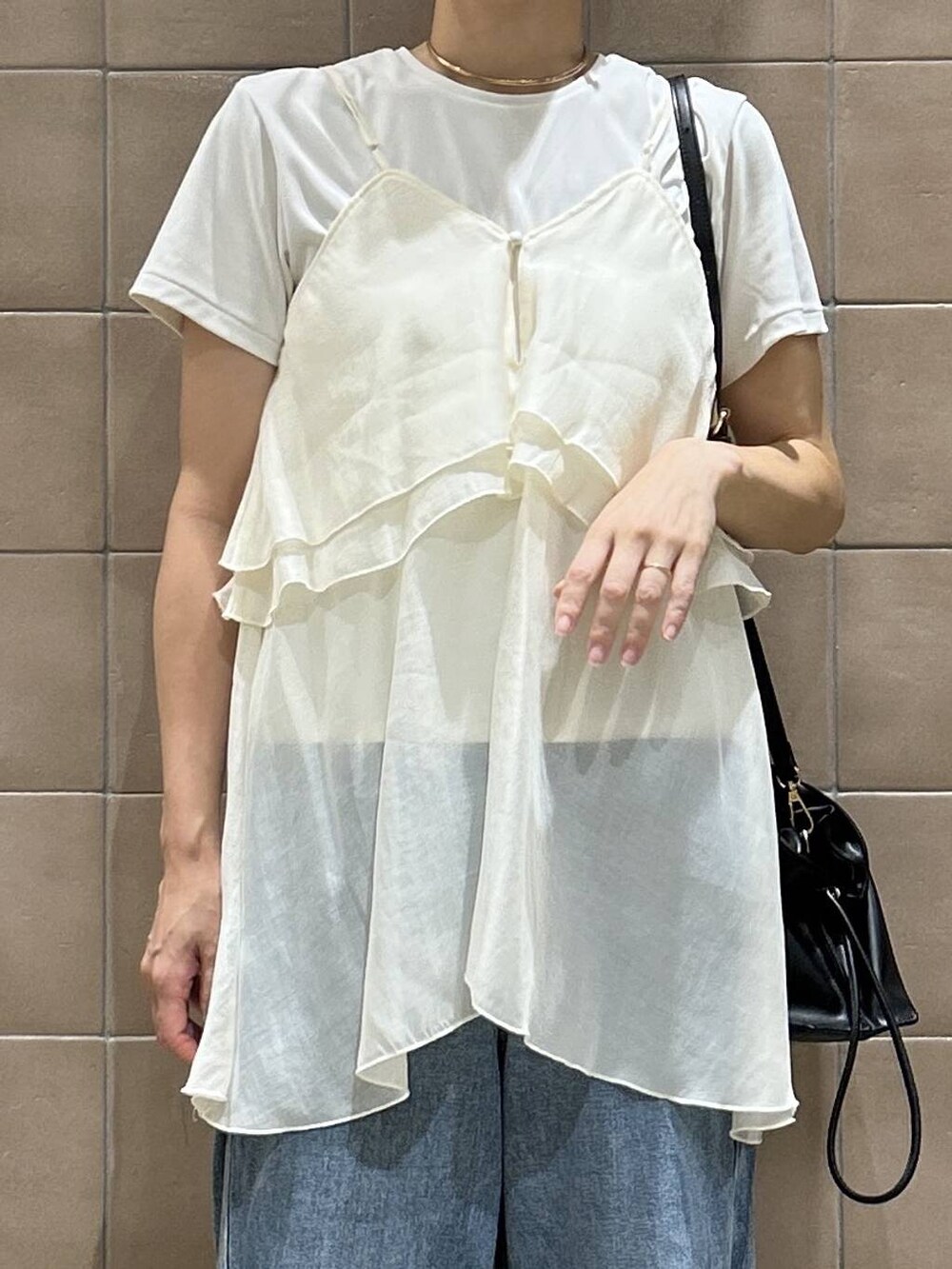 ブラック系のショルダーバッグ、ホワイト系のキャミソール、ブルー系のデニムパンツを着用したレディースの夏コーディネートの2枚目の写真