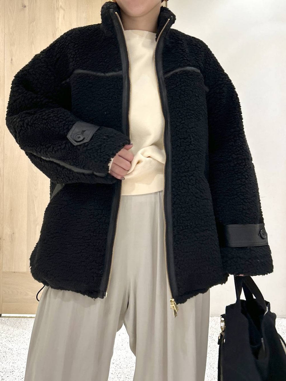 ブラック系のトートバッグ、ブラック系のブルゾン、ホワイト系のカーディガン/ボレロを着用したレディースの秋コーディネートの6枚目の写真