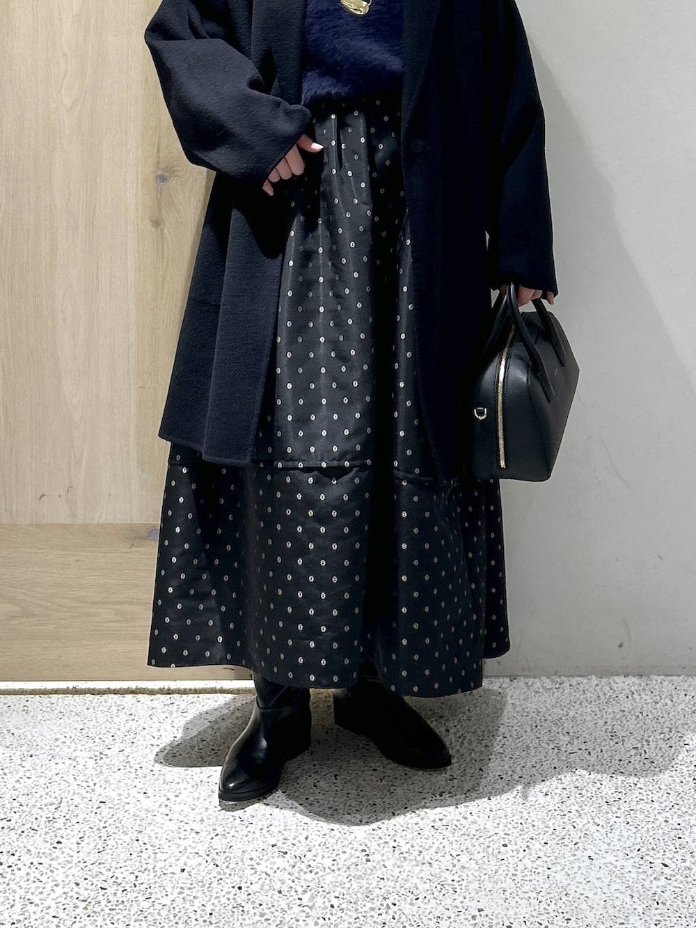 ブルー系のニット/セーター、ブルー系のチェスターコート、ブラック系のスカートを着用したレディースの秋コーディネートの2枚目の写真