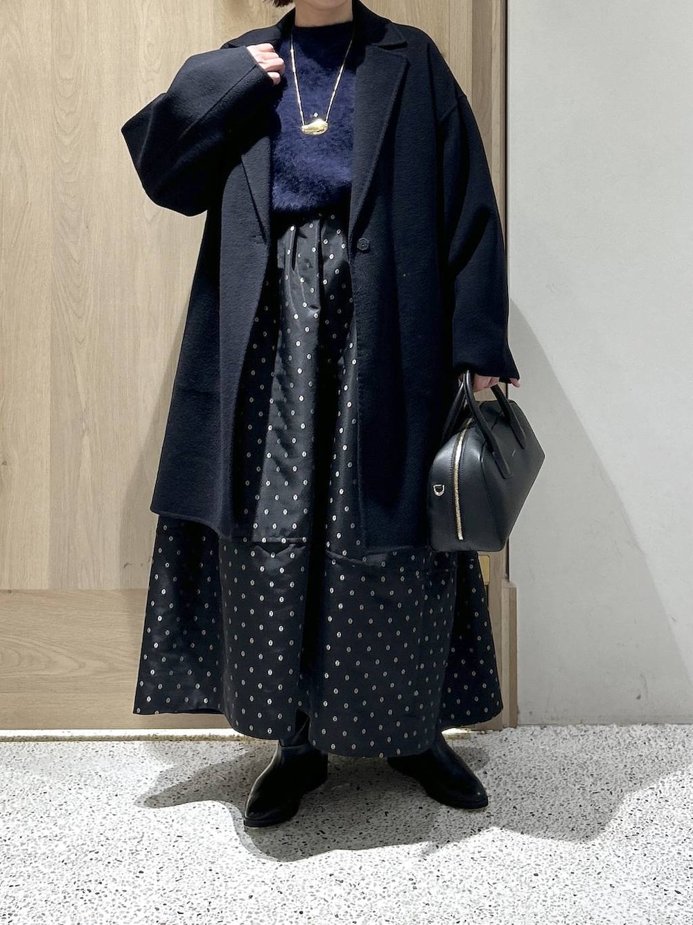ブルー系のニット/セーター、ブルー系のチェスターコート、ブラック系のスカートを着用したレディースの秋コーディネートの7枚目の写真