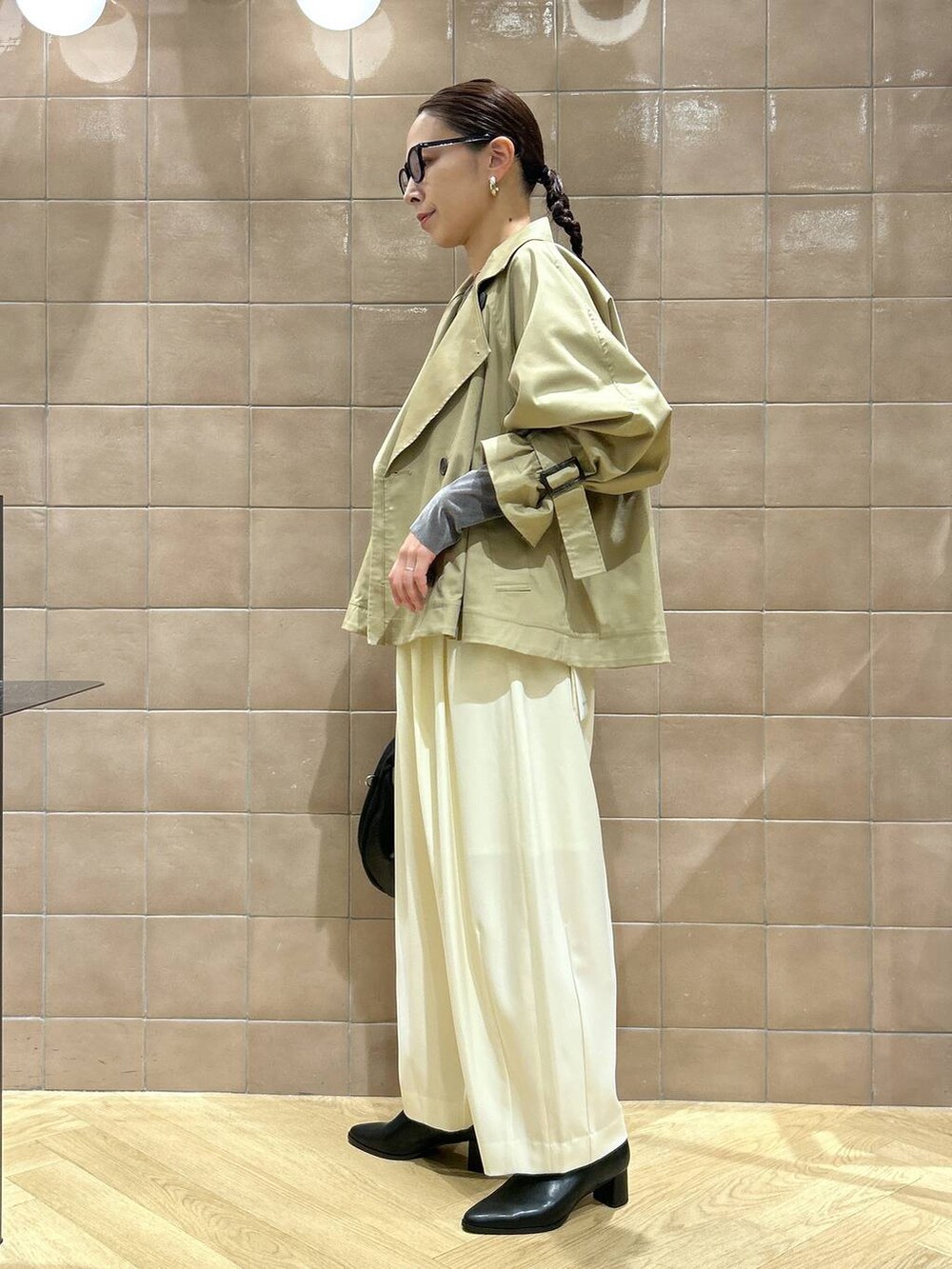 ブラック系のハンドバッグ、ホワイト系のスラックス、グレー系のTシャツ/カットソーを着用したレディースの秋コーディネートの2枚目の写真