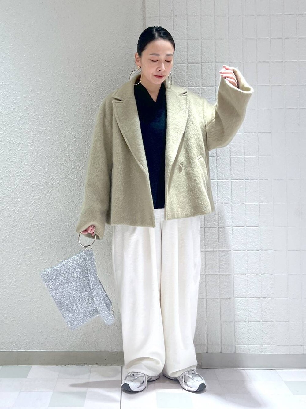 ブルー系のニット/セーター、ホワイト系のその他パンツ、シルバー系のクラッチバッグを着用したレディースの冬コーディネートの4枚目の写真