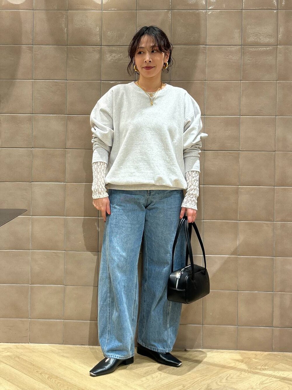 ブルー系のデニムパンツ、ブラック系のハンドバッグ、ブラック系のパンプスを着用したレディースの冬コーディネートの5枚目の写真