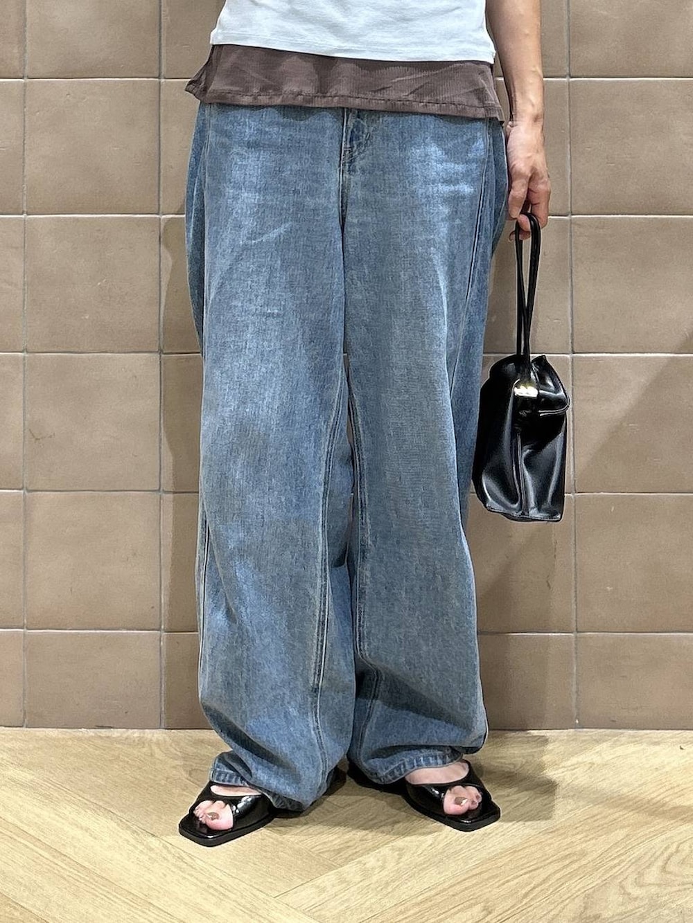 ブラック系のショルダーバッグ、ブラウン系のTシャツ/カットソー、ブルー系のデニムパンツを着用したレディースの夏コーディネートの3枚目の写真