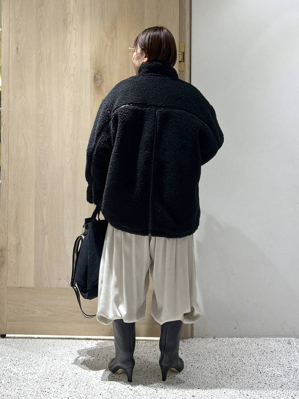 ブラック系のトートバッグ、ブラック系のブルゾン、ホワイト系のカーディガン/ボレロを着用したレディースの秋コーディネートの3枚目の写真