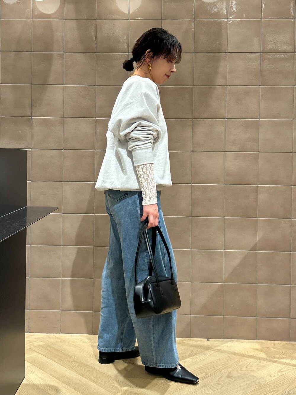 ブルー系のデニムパンツ、ブラック系のハンドバッグ、ブラック系のパンプスを着用したレディースの冬コーディネートの4枚目の写真