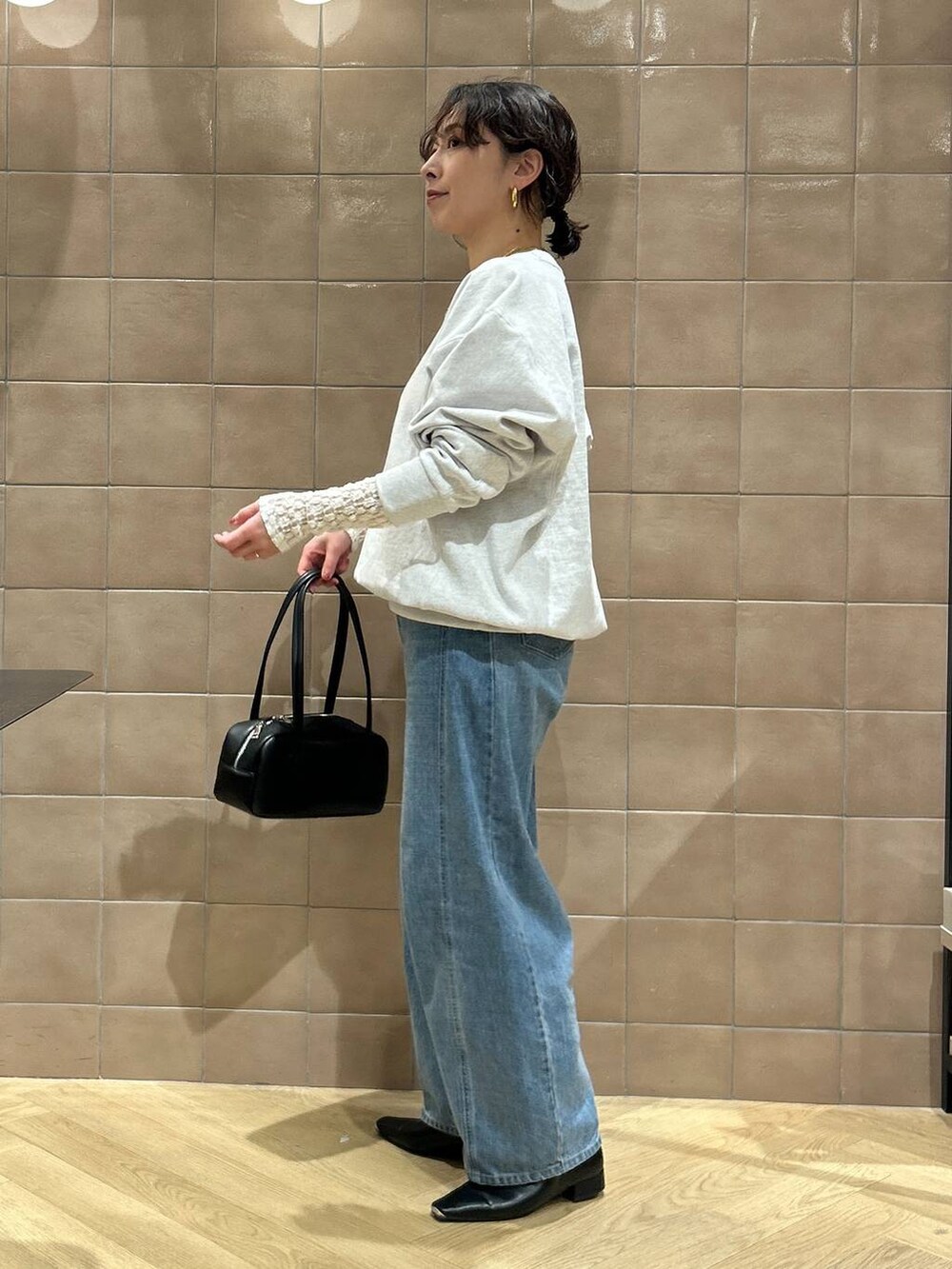 ブルー系のデニムパンツ、ブラック系のハンドバッグ、ブラック系のパンプスを着用したレディースの冬コーディネートの2枚目の写真