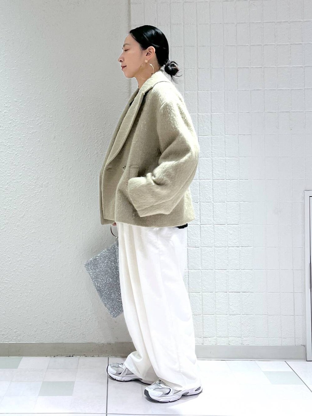 ブルー系のニット/セーター、ホワイト系のその他パンツ、シルバー系のクラッチバッグを着用したレディースの冬コーディネートの3枚目の写真