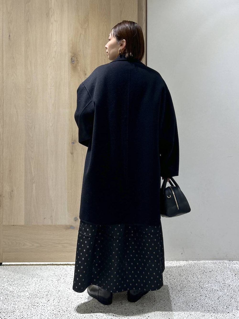 ブルー系のニット/セーター、ブルー系のチェスターコート、ブラック系のスカートを着用したレディースの秋コーディネートの5枚目の写真