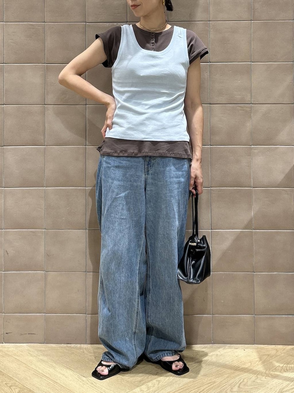ブラック系のショルダーバッグ、ブラウン系のTシャツ/カットソー、ブルー系のデニムパンツを着用したレディースの夏コーディネートの4枚目の写真