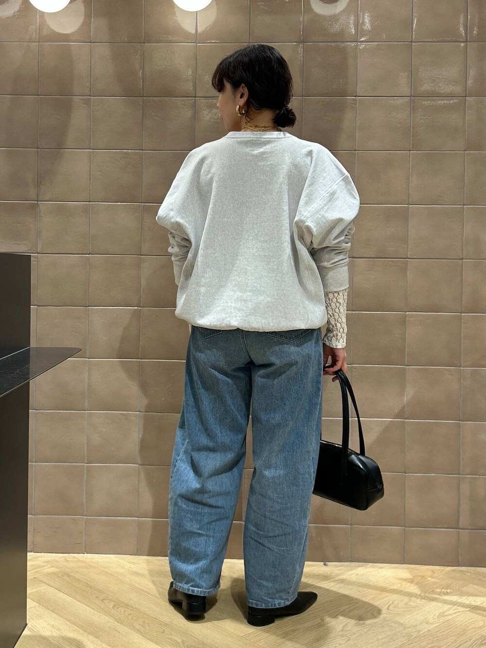 ブルー系のデニムパンツ、ブラック系のハンドバッグ、ブラック系のパンプスを着用したレディースの冬コーディネートの3枚目の写真