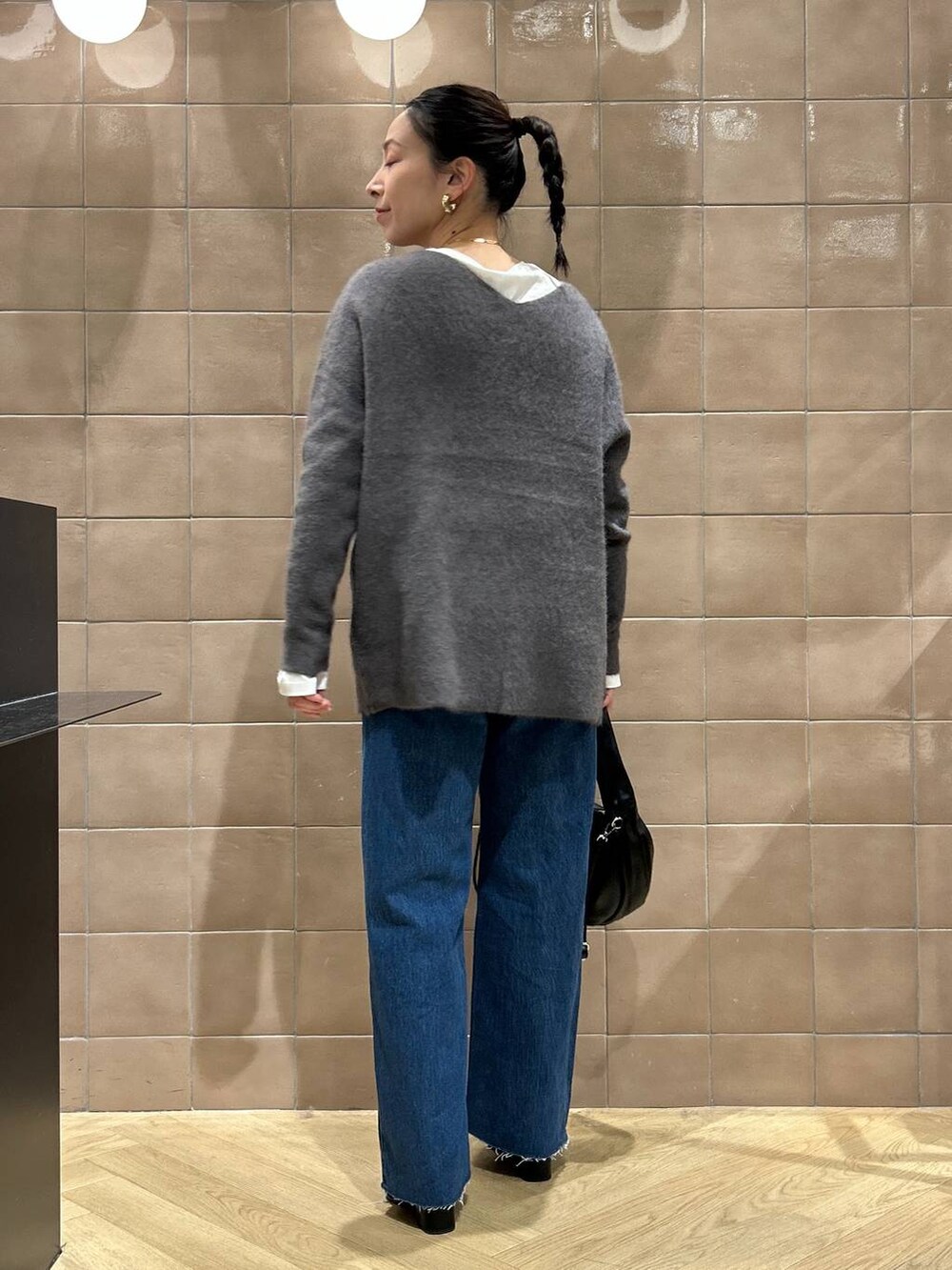 グレー系のニット/セーター、ブルー系のデニムパンツ、ブラック系のハンドバッグを着用したレディースの秋コーディネートの3枚目の写真