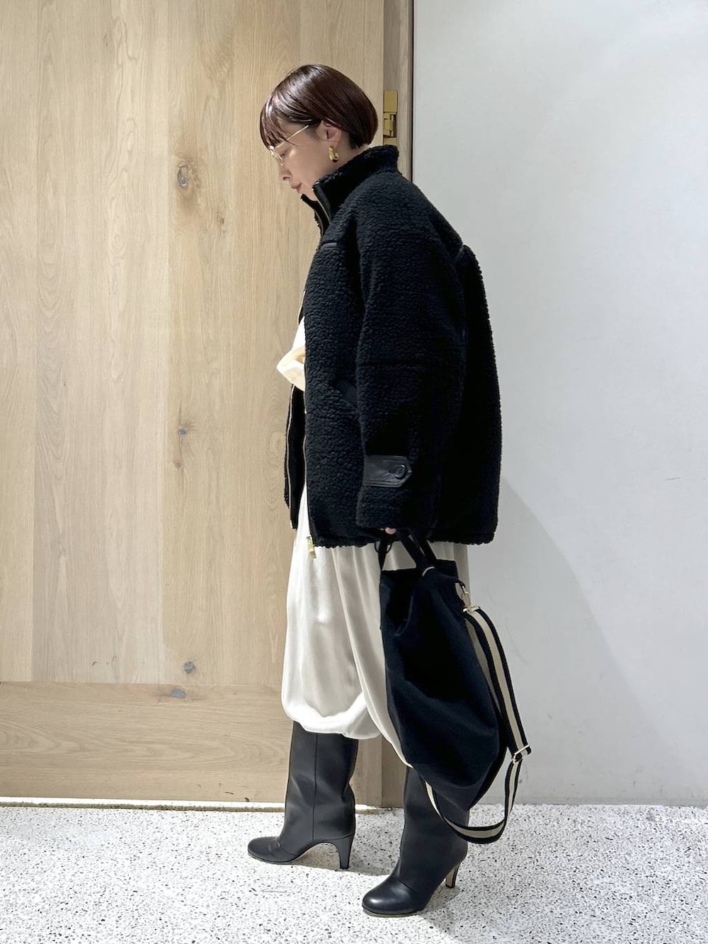 ブラック系のトートバッグ、ブラック系のブルゾン、ホワイト系のカーディガン/ボレロを着用したレディースの秋コーディネートの2枚目の写真