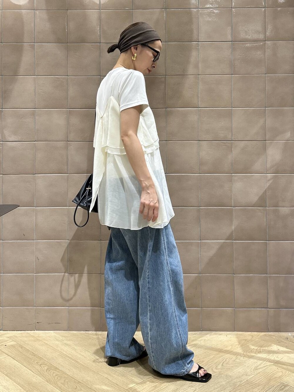 ブラック系のショルダーバッグ、ホワイト系のキャミソール、ブルー系のデニムパンツを着用したレディースの夏コーディネートの5枚目の写真