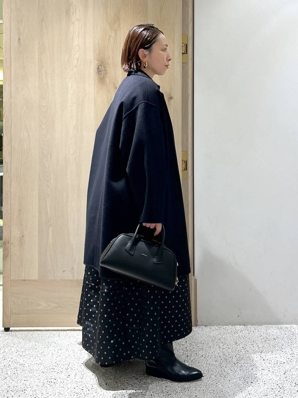 ブルー系のニット/セーター、ブルー系のチェスターコート、ブラック系のスカートを着用したレディースの秋コーディネートの6枚目の写真