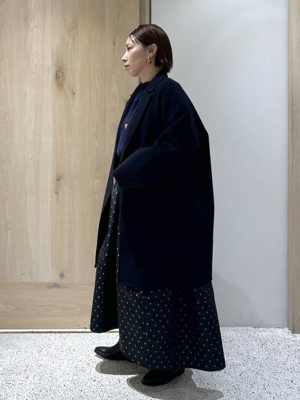 ブルー系のニット/セーター、ブルー系のチェスターコート、ブラック系のスカートを着用したレディースの秋コーディネートの4枚目の写真