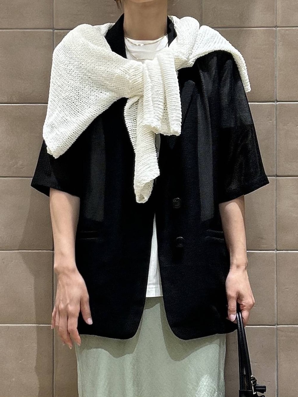 ブラック系のショルダーバッグ、ホワイト系のTシャツ/カットソー、ホワイト系のパンプスを着用したレディースの夏コーディネートの2枚目の写真