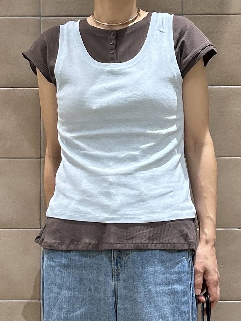 ブラック系のショルダーバッグ、ブラウン系のTシャツ/カットソー、ブルー系のデニムパンツを着用したレディースの夏コーディネートの2枚目の写真