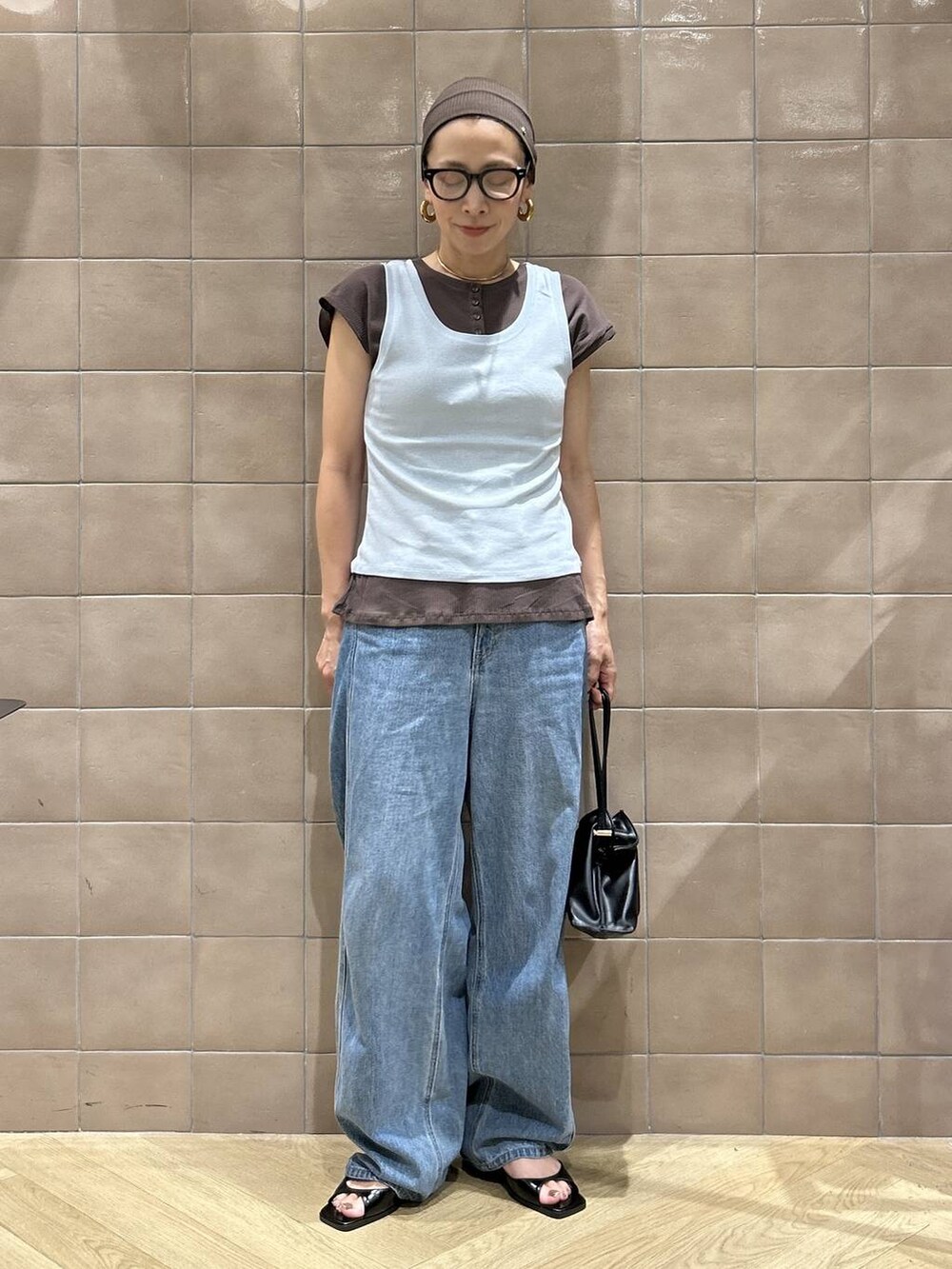 ブラック系のショルダーバッグ、ブラウン系のTシャツ/カットソー、ブルー系のデニムパンツを着用したレディースの夏コーディネートの8枚目の写真