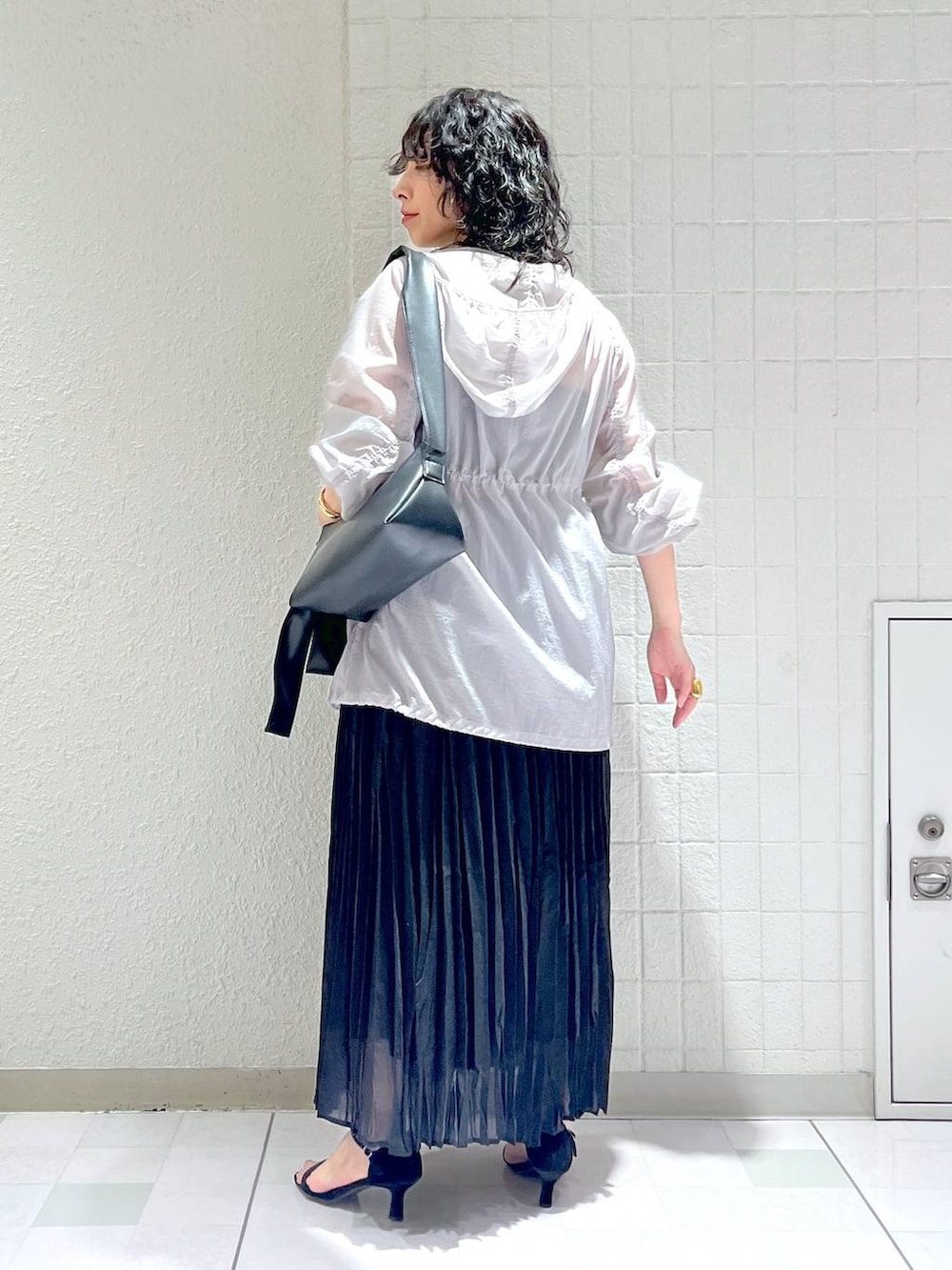 ブラック系のショルダーバッグ、グレー系のブルゾン、ブラック系のサンダルを着用したレディースの春コーディネートの2枚目の写真