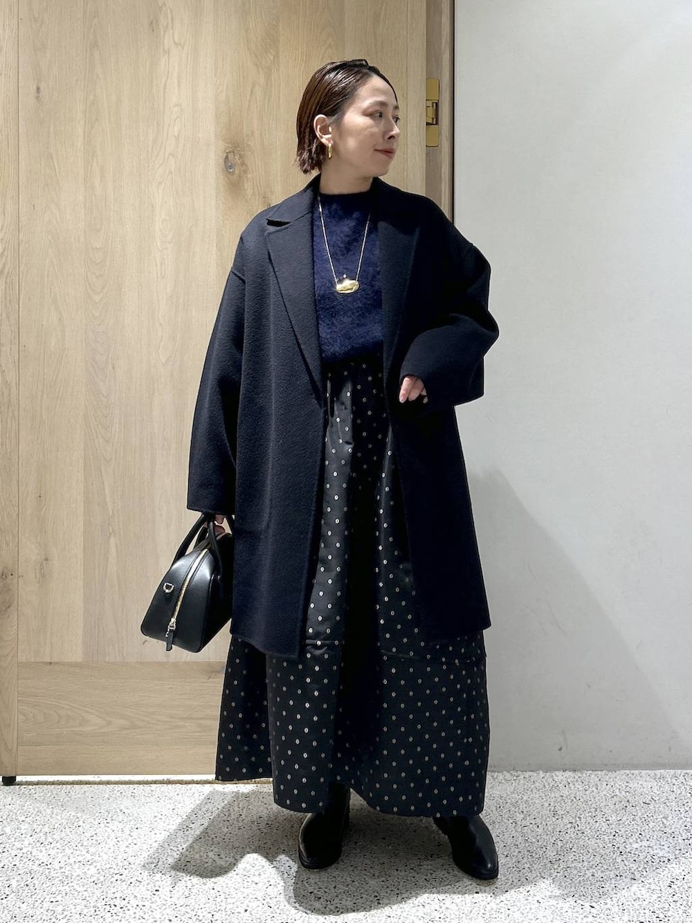 ブルー系のニット/セーター、ブルー系のチェスターコート、ブラック系のスカートを着用したレディースの秋コーディネートの3枚目の写真