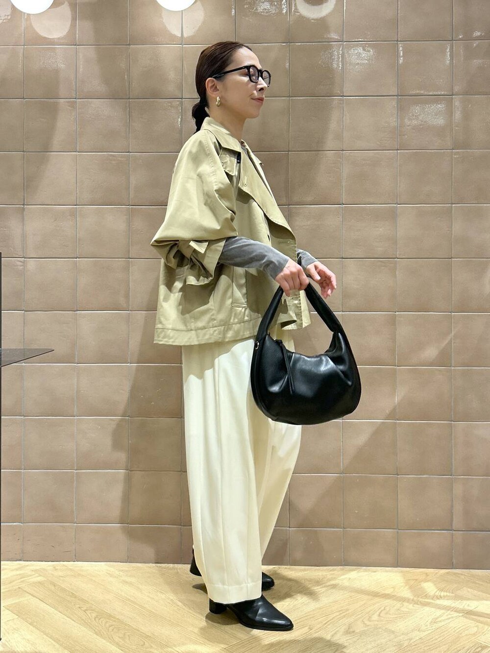 ブラック系のハンドバッグ、ホワイト系のスラックス、グレー系のTシャツ/カットソーを着用したレディースの秋コーディネートの4枚目の写真