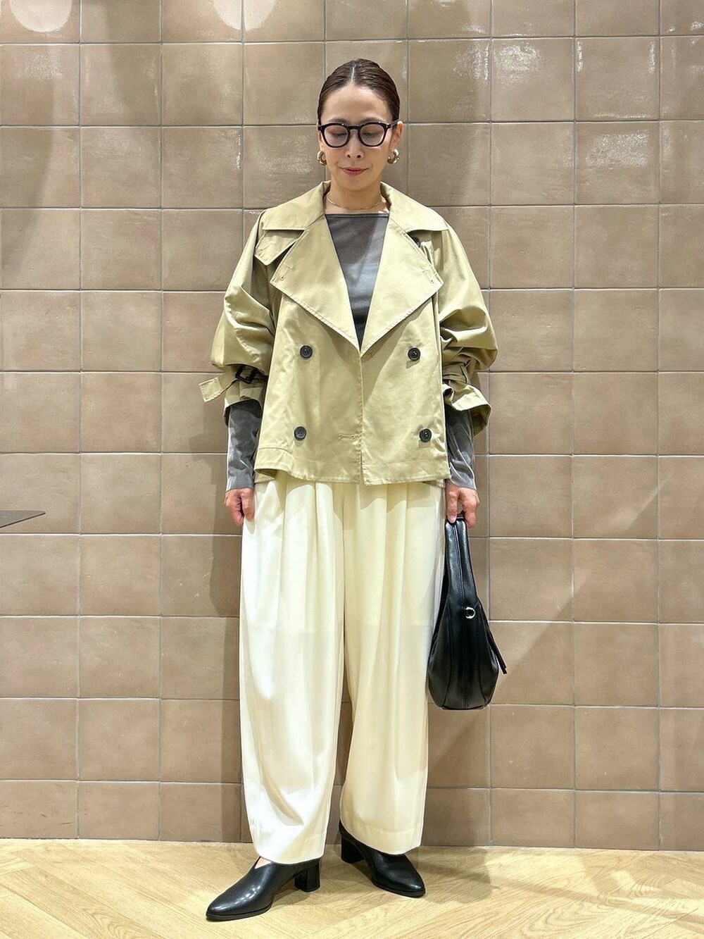 ブラック系のハンドバッグ、ホワイト系のスラックス、グレー系のTシャツ/カットソーを着用したレディースの秋コーディネートの5枚目の写真