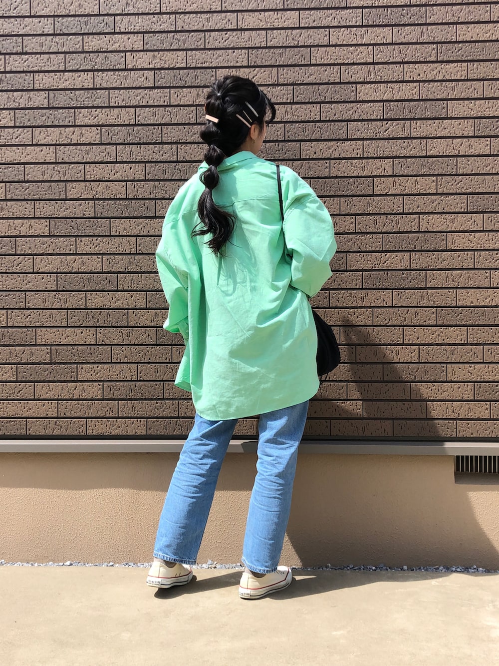 ブルー系のデニムパンツ、グリーン系のシャツ/ブラウス、ベージュ系のTシャツ/カットソーを着用したレディースの春コーディネートの2枚目の写真