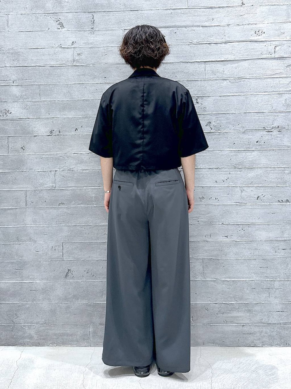 パープル系のTシャツ/カットソー、ブラック系のサンダル、グレー系のスラックスを着用したメンズの夏コーディネートの3枚目の写真