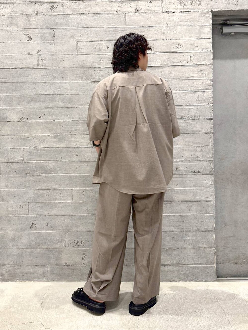 ブラック系のサンダル、イエロー系のTシャツ/カットソー、ブラウン系のスラックスを着用したメンズの夏コーディネートの2枚目の写真