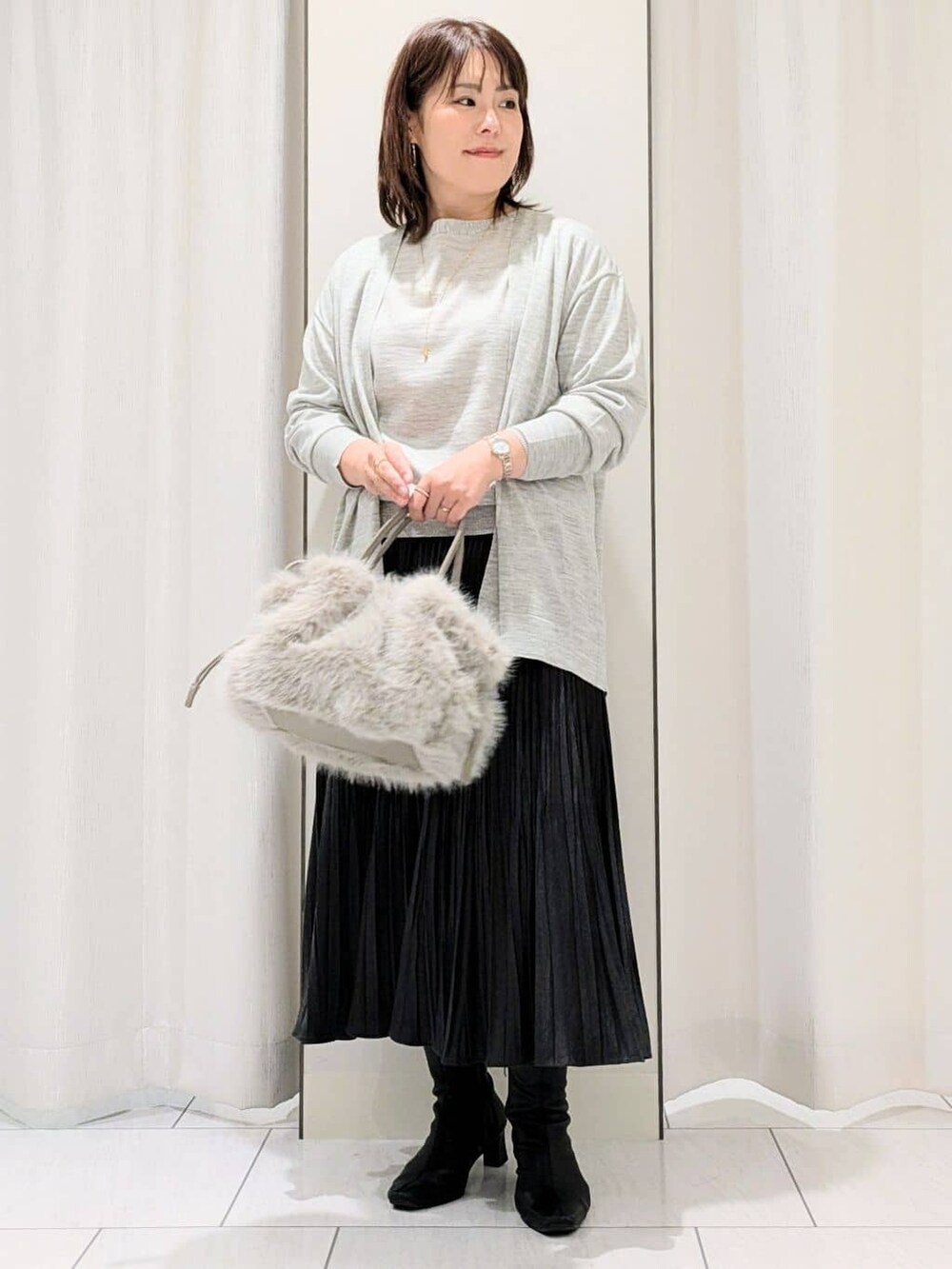 グレー系のカーディガン/ボレロ、グレー系のニット/セーター、グレー系のスカートを着用したレディースの冬コーディネートの2枚目の写真