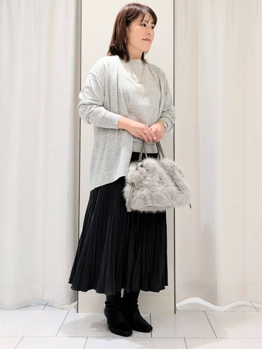 グレー系のカーディガン/ボレロ、グレー系のニット/セーター、グレー系のスカートを着用したレディースの冬コーディネートの3枚目の写真