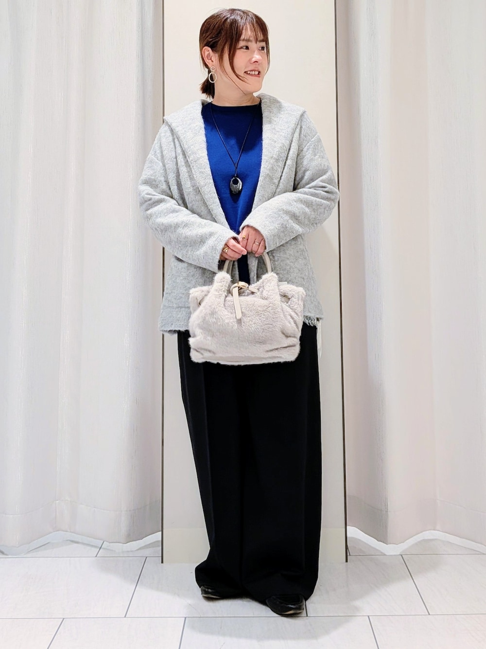 ブルー系のニット/セーター、ホワイト系のTシャツ/カットソー、ブラック系のその他パンツを着用したレディースの秋コーディネートの4枚目の写真