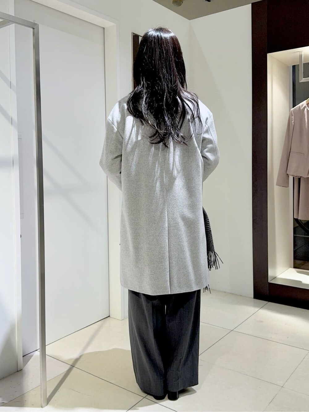 グレー系のノーカラーコート、ピンク系のニット/セーター、ホワイト系のシャツ/ブラウスを着用したレディースの冬コーディネートの3枚目の写真