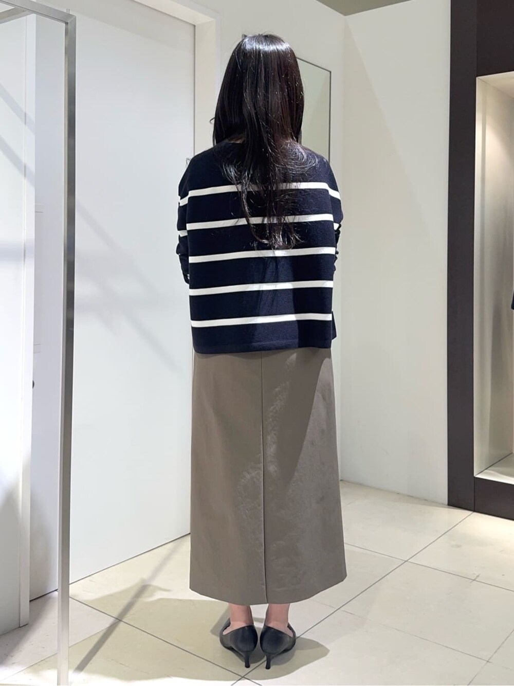 ブルー系のニット/セーター、グリーン系のスカート、ブラック系のパンプスを着用したレディースの春コーディネートの3枚目の写真