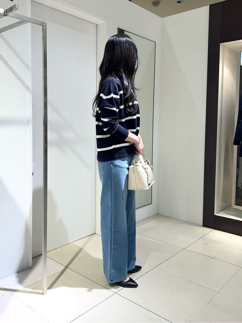 ブルー系のニット/セーター、ブルー系のデニムパンツ、ブラック系のパンプスを着用したレディースの春コーディネートの2枚目の写真