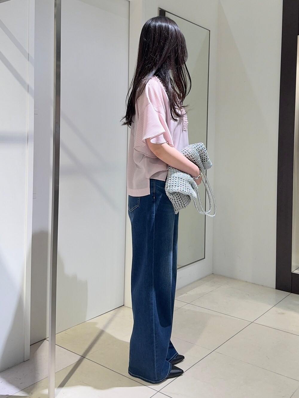 ブルー系のデニムパンツ、ブラック系のパンプスを着用したレディースの春コーディネートの2枚目の写真