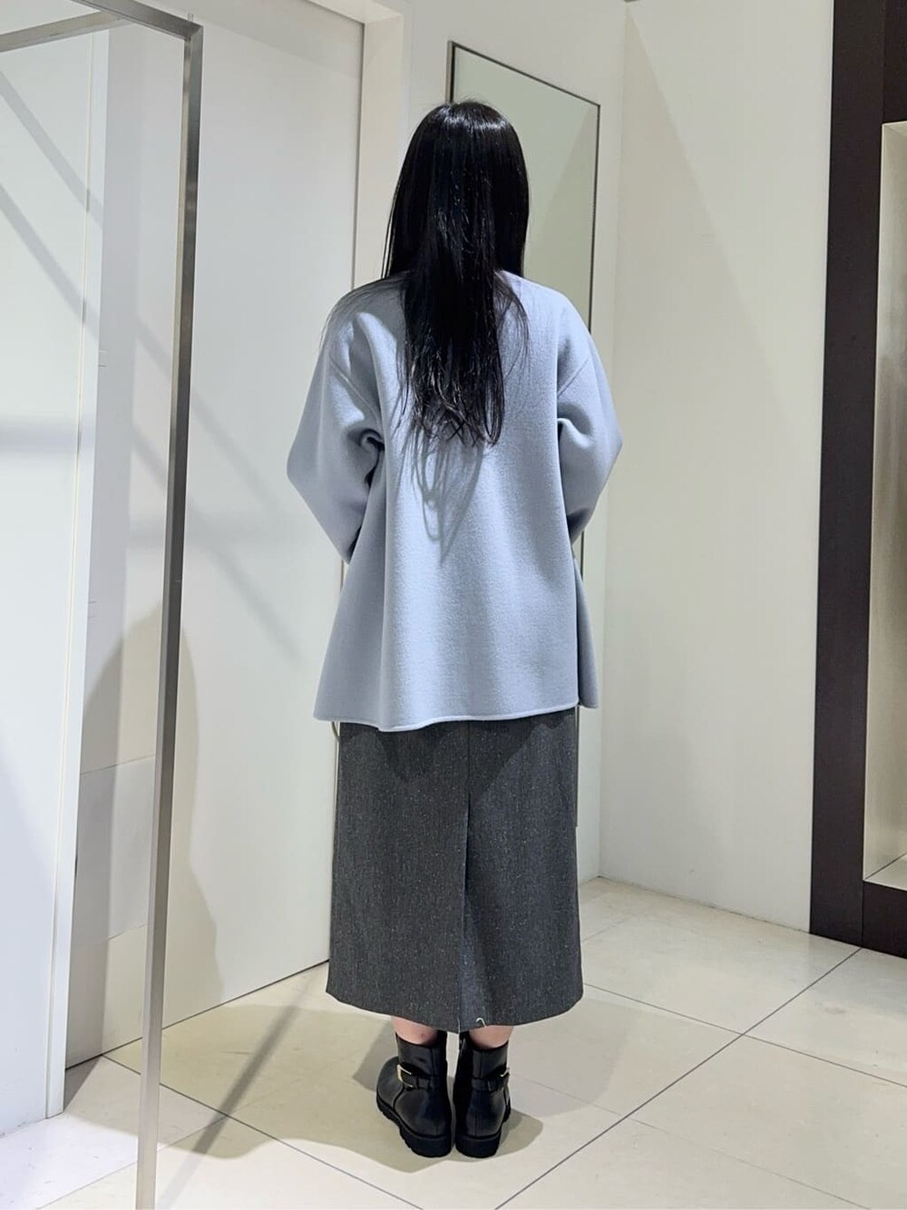 ブルー系のノーカラーコート、ホワイト系のニット/セーター、グレー系のスカートを着用したレディースの秋コーディネートの4枚目の写真