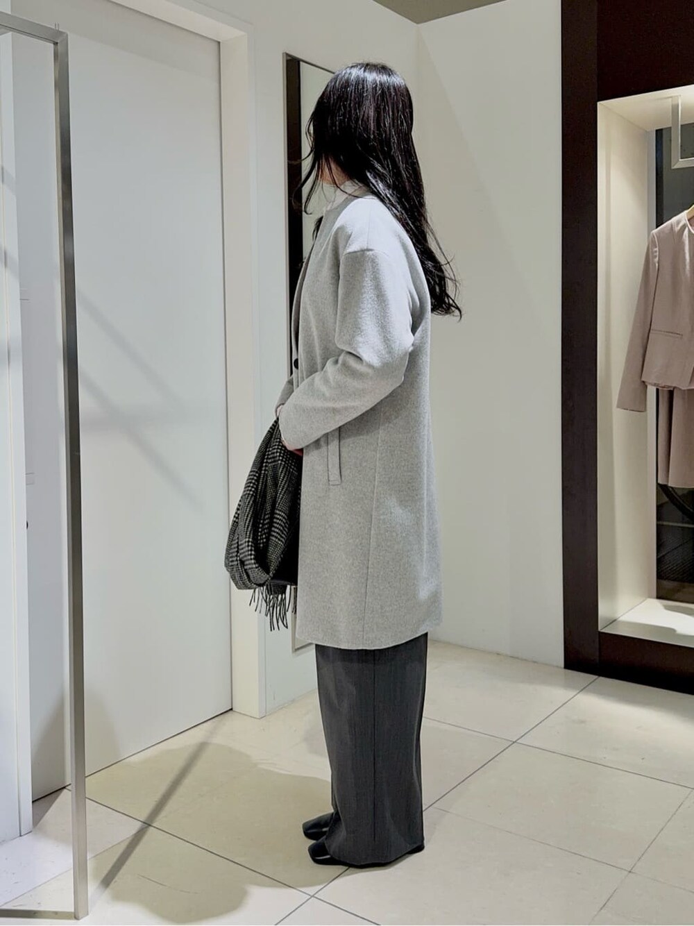 グレー系のノーカラーコート、ピンク系のニット/セーター、ホワイト系のシャツ/ブラウスを着用したレディースの冬コーディネートの2枚目の写真